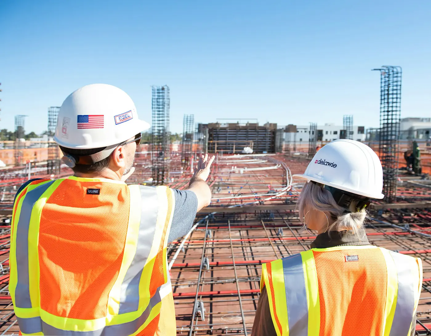 Two workers in hi-vis coordinating across a large construction site