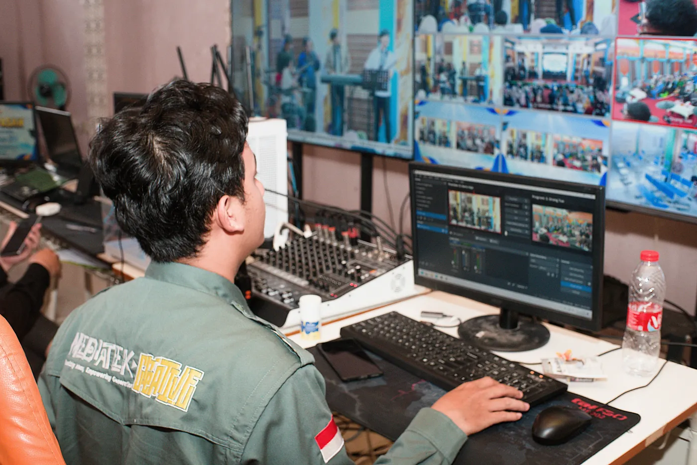 Operator monitoring screens and audio equipment in an event control room.