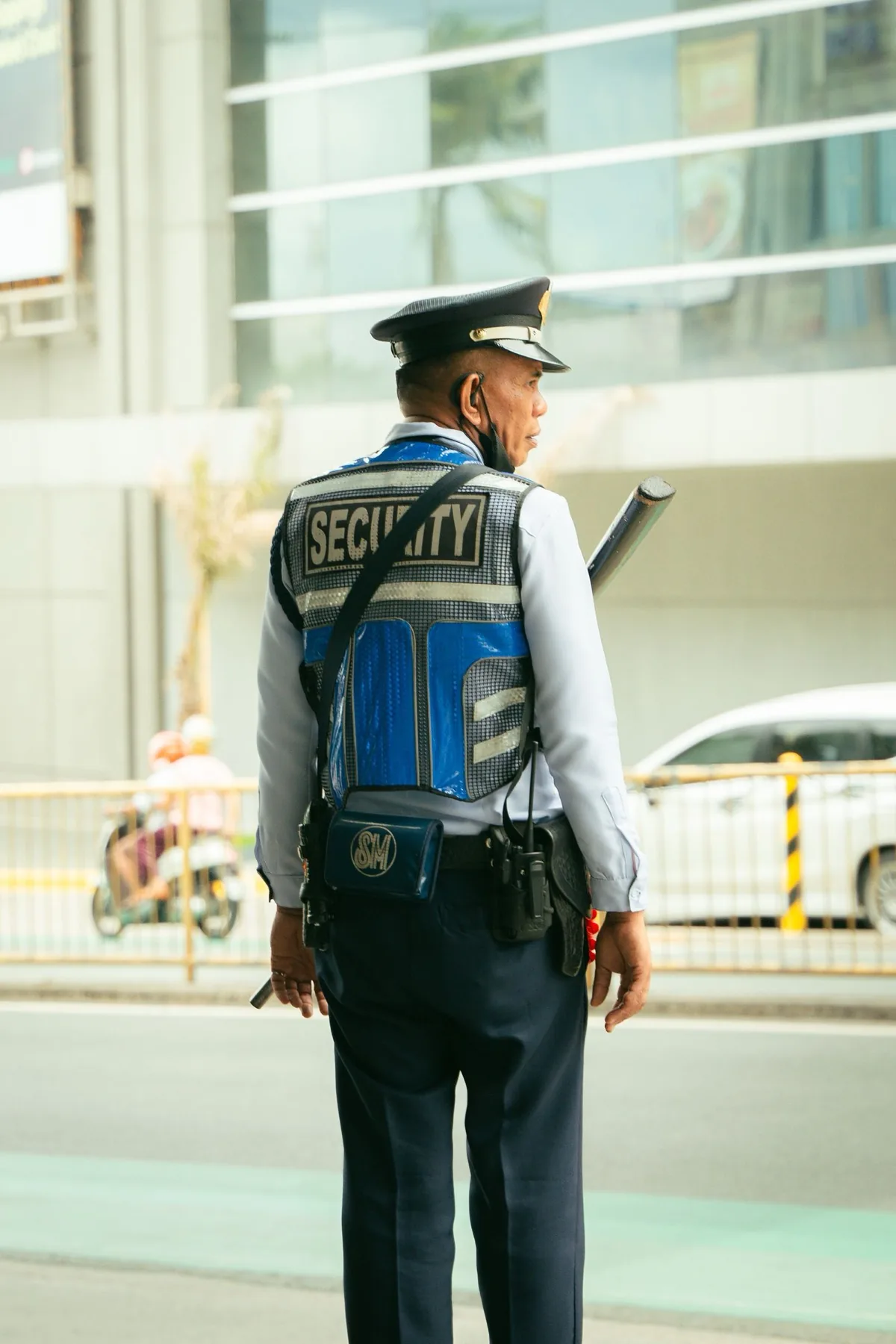Uniformed security officer on patrol wearing a radio earpiece, with a two-way radio holstered on his duty belt